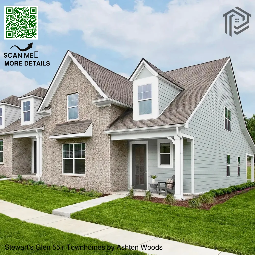 A modern two-story townhome with brick and light gray siding, featuring a well-manicured lawn, a small front porch with seating, and large windows. A QR code with "Scan Me for More Details" is in the top left corner, and the text "Stewart's Glen 55+ Townhomes by Ashton Woods" is at the bottom. The image is set against a partly cloudy sky