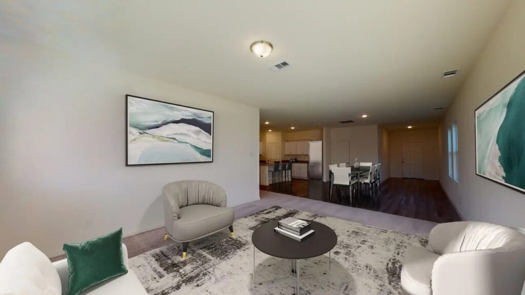 Open-concept living room with soft neutral walls, large windows, and easy flow into the kitchen.