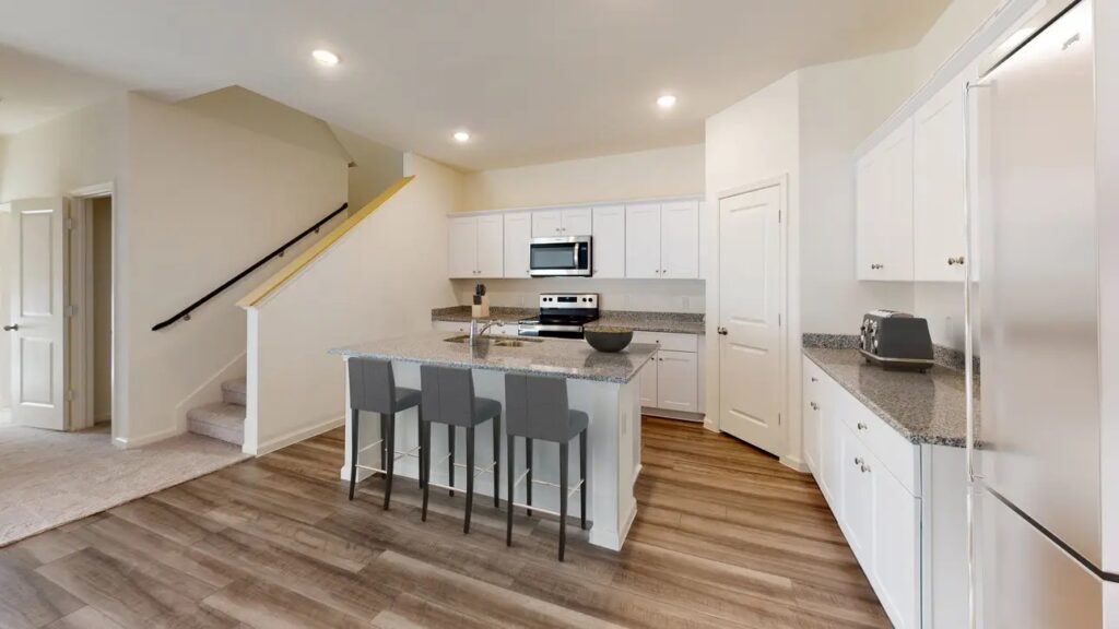 Bright kitchen with granite countertops, white cabinets, and stainless steel appliances